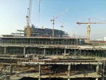 Cranes at construction site against sky in city