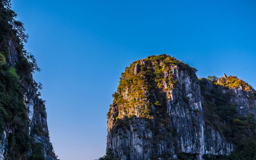 Low angle view of rock formation against clear blue sky