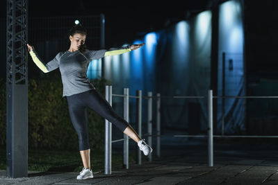 Woman exercising in city at night