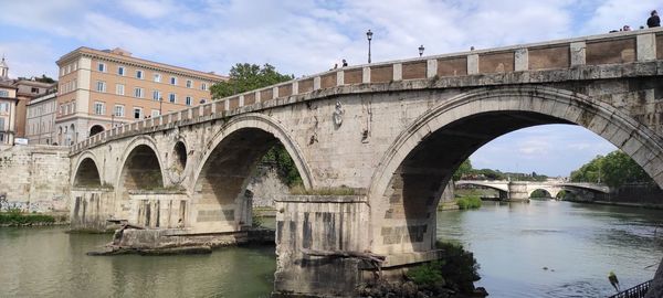 Arch bridge over river against sky