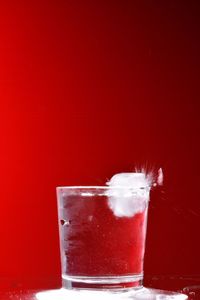 Close-up of beer glass against red background