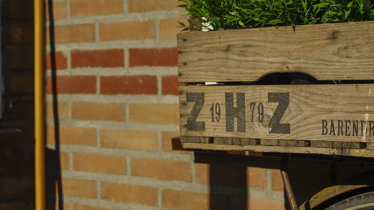 CLOSE-UP OF TEXT ON WOOD AGAINST BRICK WALL