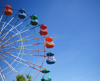 Low angle view of ferris wheel against clear blue sky