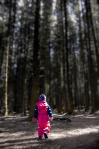 Rear view of girl walking in forest during winter