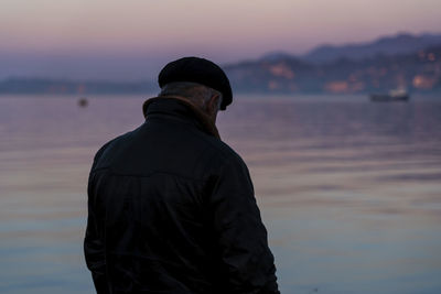 Rear view of man standing against sea during sunset