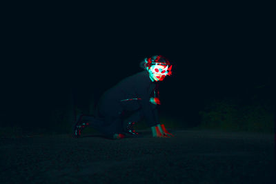 Rear view of woman with umbrella at night