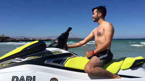 Full length of shirtless man in sea against sky