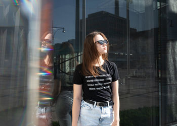 Young woman standing by glass