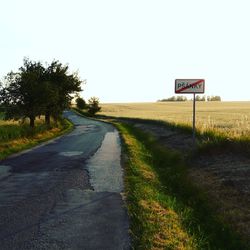 Road sign on field against clear sky