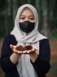 A woman is holding a pine tree flower in her hand