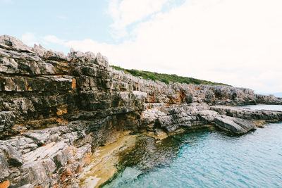 Rock formations by sea against sky