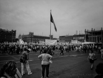 Rear view of people on street in city against sky