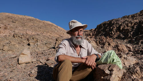 Senior man sitting on rock in the desert 