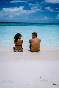 Rear view of men sitting on beach