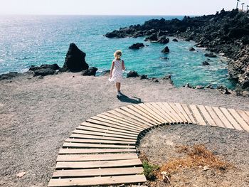 Rear view of girl walking at beach