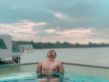 Shirtless man relaxing swimming in pool