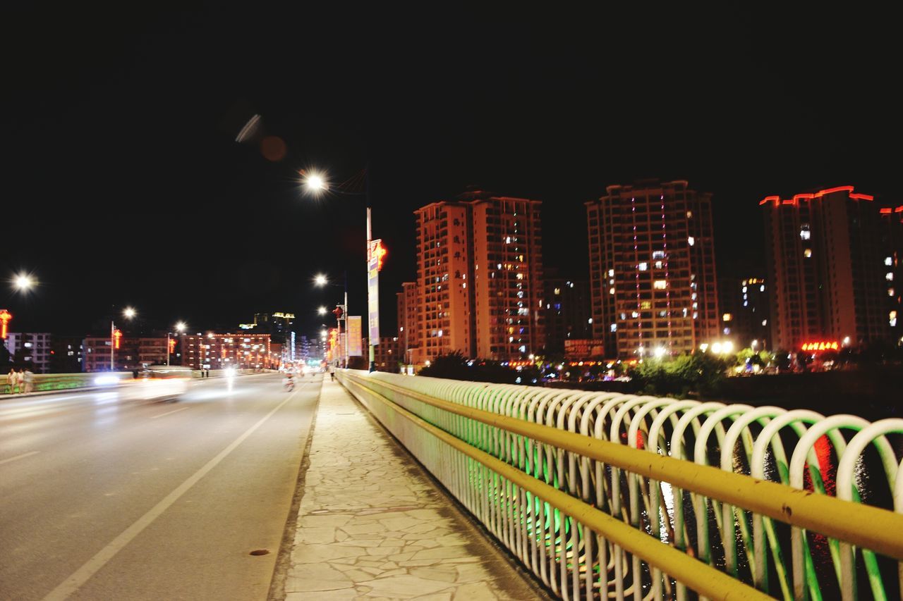 illuminated, night, city, architecture, built structure, skyscraper, cityscape, office building, street light, modern, tall - high, city life, lighting equipment, sky, urban skyline, city street, building, outdoors, the way forward, travel destinations, no people, capital cities, tall, development