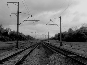 Railroad tracks against cloudy sky