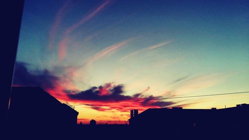 Low angle view of silhouette houses against sky at sunset