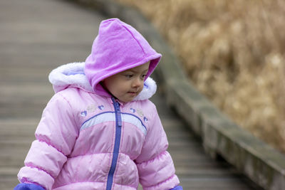 Cute baby girl wearing warm clothing standing on footpath
