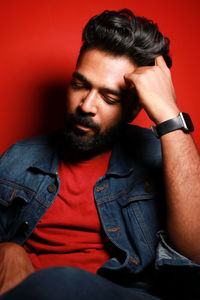 Portrait of young woman looking away against yellow background