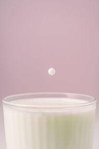 Milk drips into a transparent faceted glass.