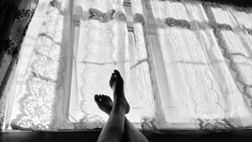 Low section of woman on window sill