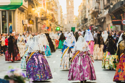 Rear view of people walking on street in city