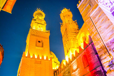 Low angle view of illuminated buildings against sky at night