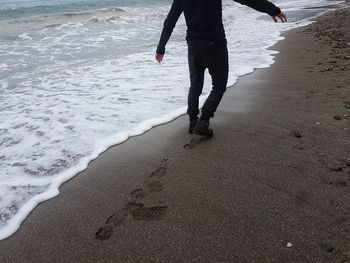 Low section of people walking on beach