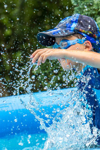 Side view of playful boy splashing water in wading pool