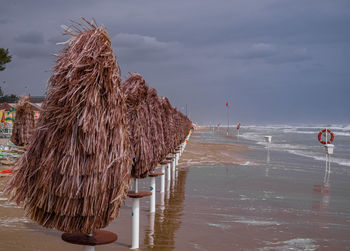 Panoramic view of wooden posts on beach against sky