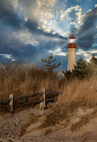 Lighthouse on beach against sky