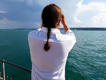 Rear view of man standing in sea against sky