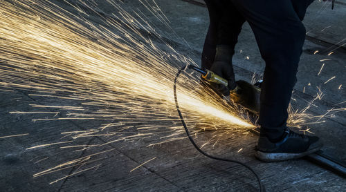 Low section of man using grinder at workshop