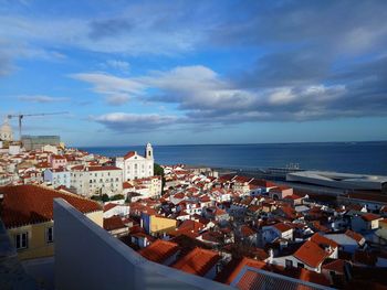 High angle view of town by sea against sky