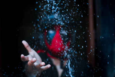 Man with mask reaching for falling water