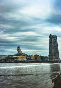 View of building by river against cloudy sky