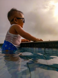 Boy enjoying in swimming pool against sky