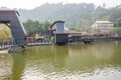 Houses by river against buildings