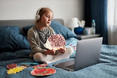 Little girl preschooler learning online showing her works drawings done at home