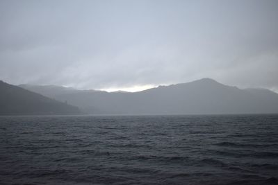 Scenic view of sea and mountains against sky