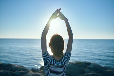 Rear view of woman against sea against clear sky