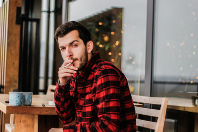 Portrait of young man smoking cigarette in cafe