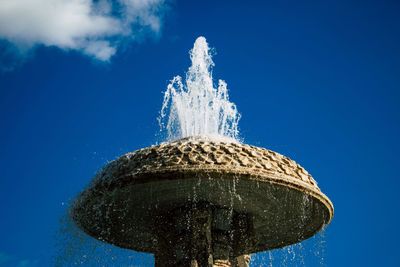 Low angle view of fountain against blue sky