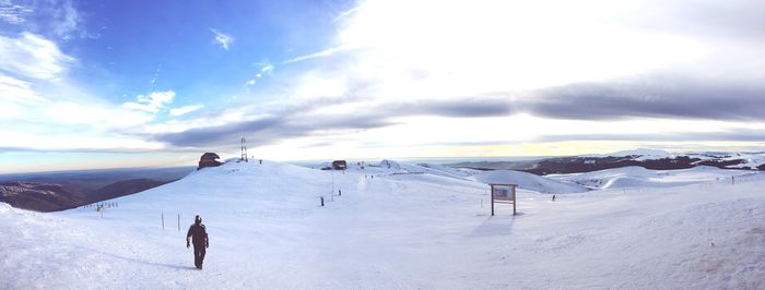 Rear view of person on snow covered field against sky