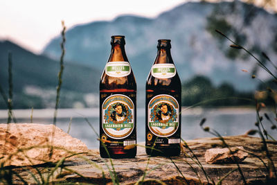 Close-up of beer bottles on table by lake