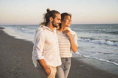 Friends standing at beach against sky