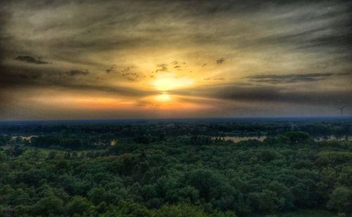 Scenic view of landscape against dramatic sky during sunset