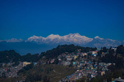 High angle view of townscape and mountains against blue sky